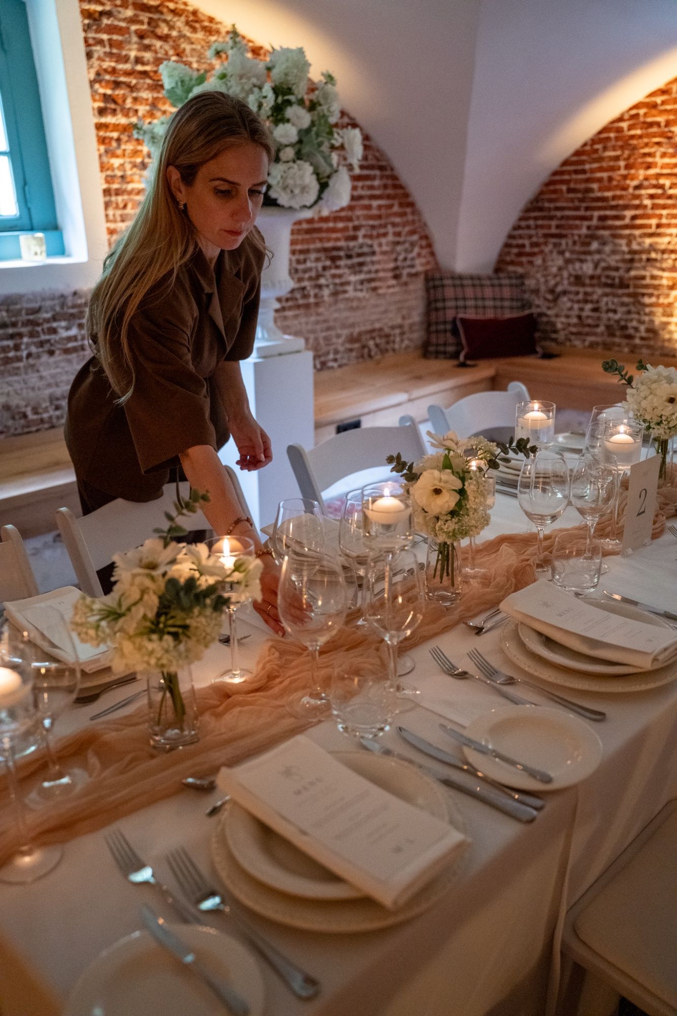 De weddingplanner controleert de gedekte tafel met kaarsen en bloemen